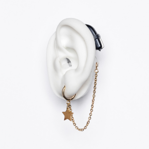White ear mould shows star earring with chain in gold